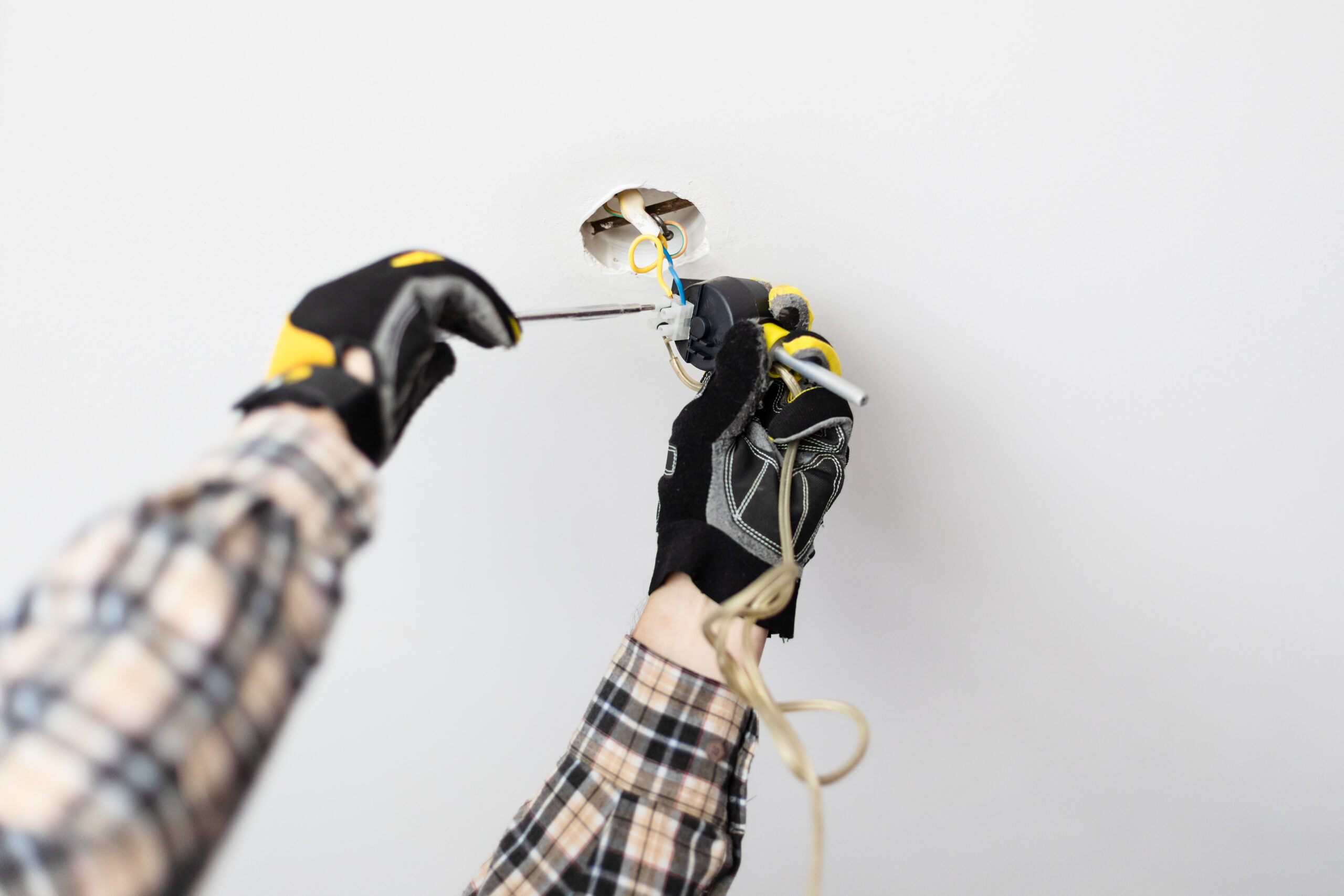 licensed electrician wiring a ceiling light fitting during downlights installation